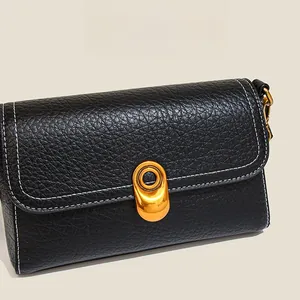 Detail of black pebbled leather bag with white contrast stitching and gold twist lock