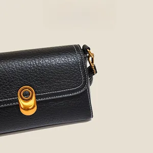 Detail of black pebbled leather bag with contrast stitching and gold metal twist lock