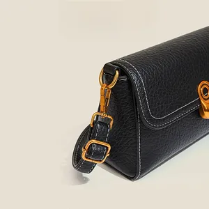 Detail of black lychee grain leather bag with white contrast stitching and gold hardware