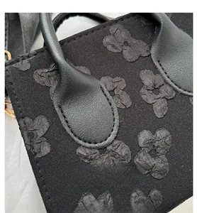Detail shot of black handbag with floral jacquard texture and fine stitching handle