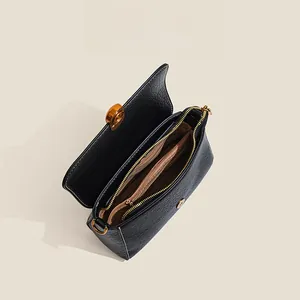 Detailed interior of black pebbled leather crossbody bag with golden hardware zippers