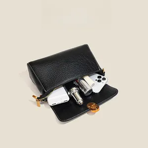 Internal view of black pebble leather crossbody bag showing spacious capacity and gold zipper