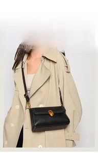 Detail of black textured leather bag with gold oval twist lock and white stitching