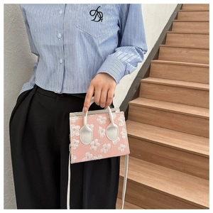 Detail of pink floral jacquard mini crossbody bag with white handle and long strap