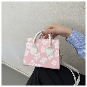 Detailed close-up of a pink mini tote bag featuring 3D floral textures and white handles