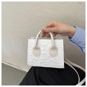 Detail of white mini handbag with embossed floral texture and smooth round top handle