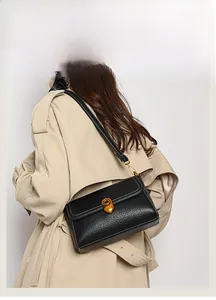 Detail of black lychee leather bag with white contrast stitching and gold round buckle