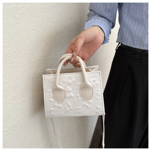 Close-up of white mini tote bag with 3D floral embroidery and detachable strap