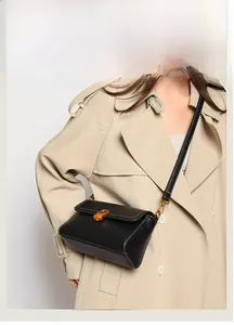 Detail of black leather crossbody bag with gold twist lock and white contrast stitching