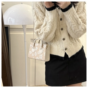 Close-up of beige mini crossbody bag with white floral embroidery and gold metal details