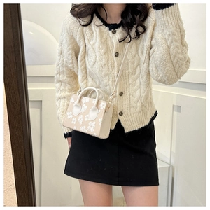 Close-up of mini beige handbag with white 3D flower detail and thin shoulder strap