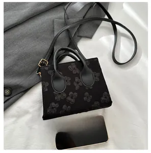 Detail of black tote bag with 3D floral embroidery and adjustable leather strap