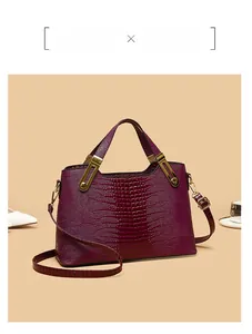 Detail of purple crocodile embossed tote bag with gold metal trim and adjustable strap