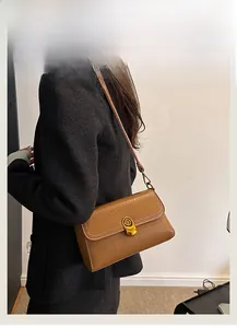 Close-up of caramel brown leather crossbody bag featuring a round metal twist lock closure