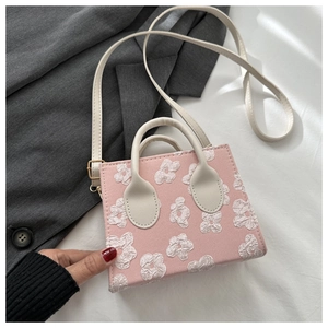 Detail of pink square handbag featuring 3D white floral texture and ivory top handles