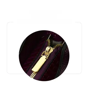 Close-up of premium gold zipper hardware on deep purple textured handbag detail