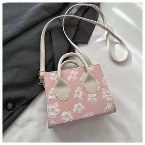 Detail of pink crossbody bag with white 3D floral textures and cream leather handle