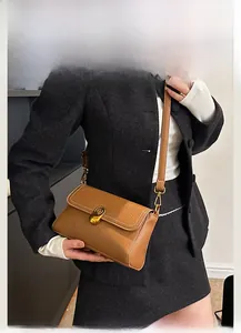 Close-up of brown litchi pattern leather bag with white stitching and gold oval lock