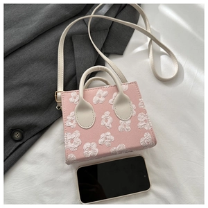 Detailed view of pink floral mini square handbag with phone for scale comparison