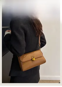 Detailed back view of a brown pebbled leather crossbody bag on a black wool coat