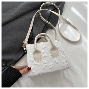 Detailed view of the embossed floral jacquard texture on this white square fashion handbag