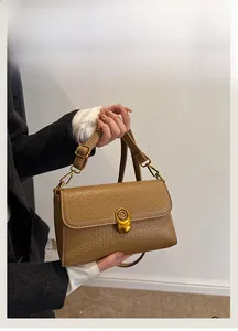 Detail of brown litchi pattern leather bag with vintage gold clasp and white stitching