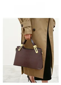 Brown crocodile embossed tote bag detail with golden hardware and twin handles on a model