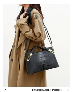 Fashionable black crocodile embossed handbag with gold hardware shown on a model