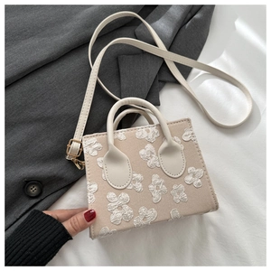Close-up of beige crossbody bag featuring 3D floral embroidery and fine canvas texture