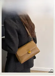 Detail of tan lychee pattern leather shoulder bag featuring vintage gold oval twist lock