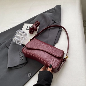 Sac baguette bordeaux à motif crocodile de style français sur un costume gris