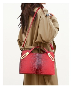 Detail of red crocodile embossed handbag with gold metal hardware and adjustable strap