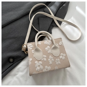 Detail of a beige mini square handbag with 3D floral textures and sleek round handles