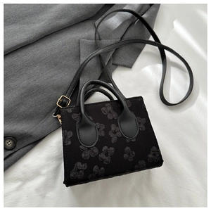 Close-up of black mini bag featuring 3D floral texture and elegant gold-tone hardware