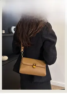 Detail view of caramel brown pebbled leather crossbody bag with gold twist-lock closure