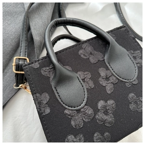 Mini black handbag with floral jacquard texture and golden hardware accents for women