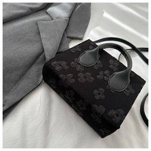 Detail of minimalist black handbag showing high-quality 3D floral embossed texture