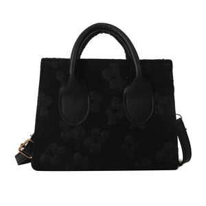 Black embossed floral handbag with dual top handles and adjustable shoulder strap