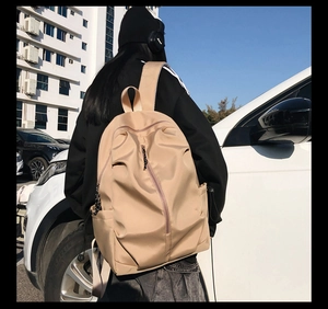 Outdoor shot of a beige nylon casual backpack with side pockets and vertical zippers