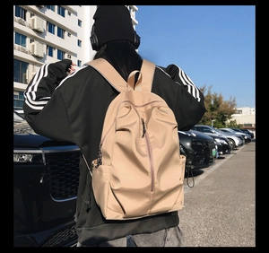 Close-up of beige nylon backpack featuring unique vertical pleated design and zip compartments