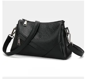 Détail d'un sac bandoulière noir multi-poches avec des fermetures éclair argentées