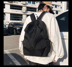 Detail of waterproof black backpack showing side drawstring pocket and vertical zipper