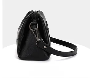 Vue latérale du sac en cuir noir montrant la fermeture éclair et le crochet argenté