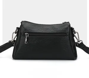 Détail de la poche zippée arrière du sac à bandoulière noir avec texture grainée