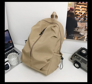 Large khaki nylon backpack on desk next to laptop for casual travel or school