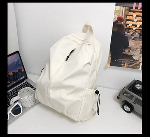 Detail of cream white canvas backpack with unique diagonal zipper and side drawstring pocket