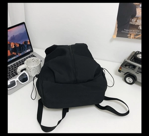 Minimalist black backpack on desk with laptop and sunglasses for daily student lifestyle