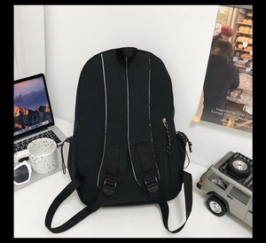Rear view of black nylon backpack with wide adjustable straps and side zipper pocket