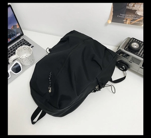 Top view of a black large-capacity minimalist backpack on a desk with laptop and gear