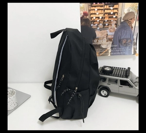 Close-up of black nylon backpack featuring drawstring side pockets and adjustable straps
